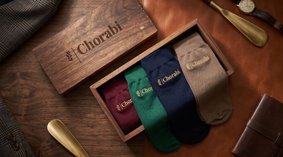 Four pairs of socks in burgundy, green, navy and beige in a walnut Chorabi box